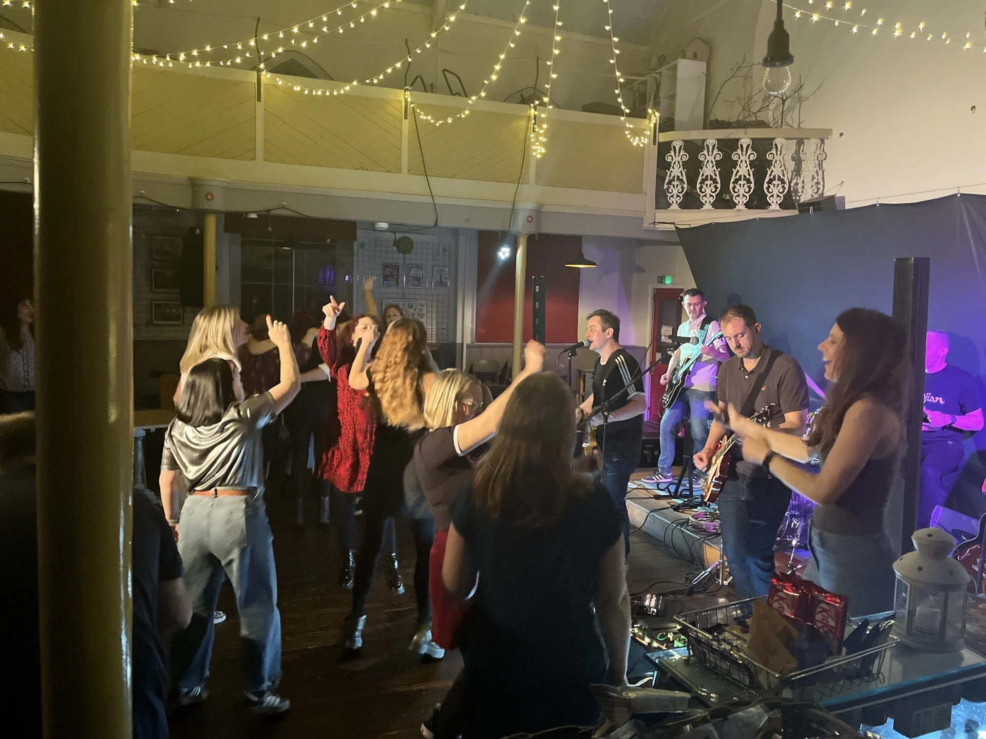 A fun indoor concert with a live band performing on the stage and people dancing.