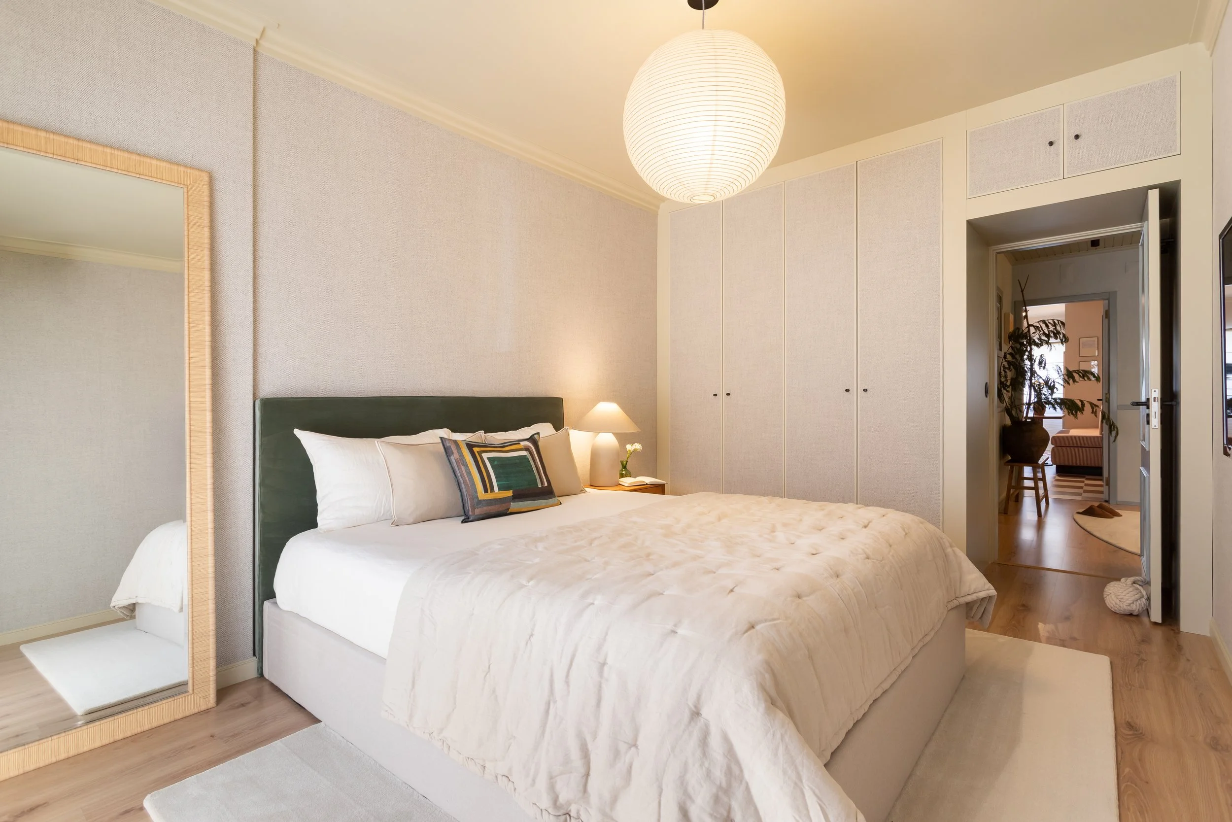 Quarto com cabeceira verde, roupeiro embutido e pavimento em madeira natural