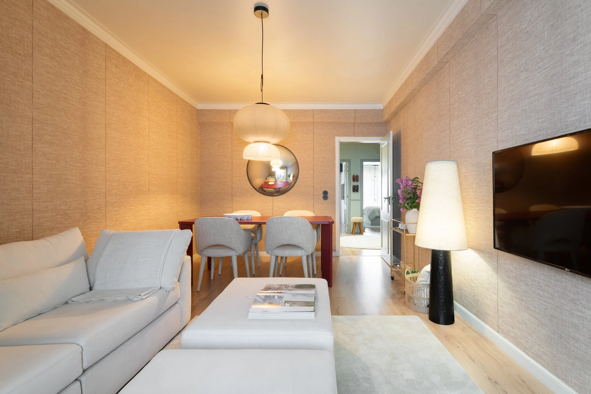 Sala de estar com sofá branco, mesa de centro e espelho redondo
