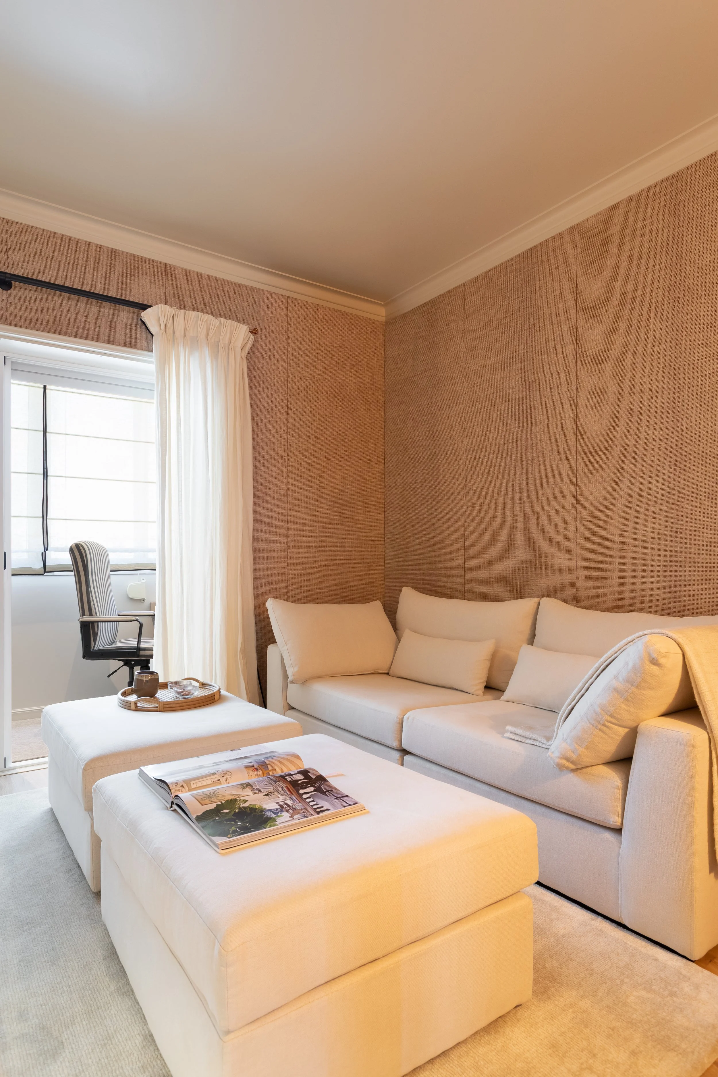 Sala de estar com sofá branco, mesas de apoio e cortinados de linho