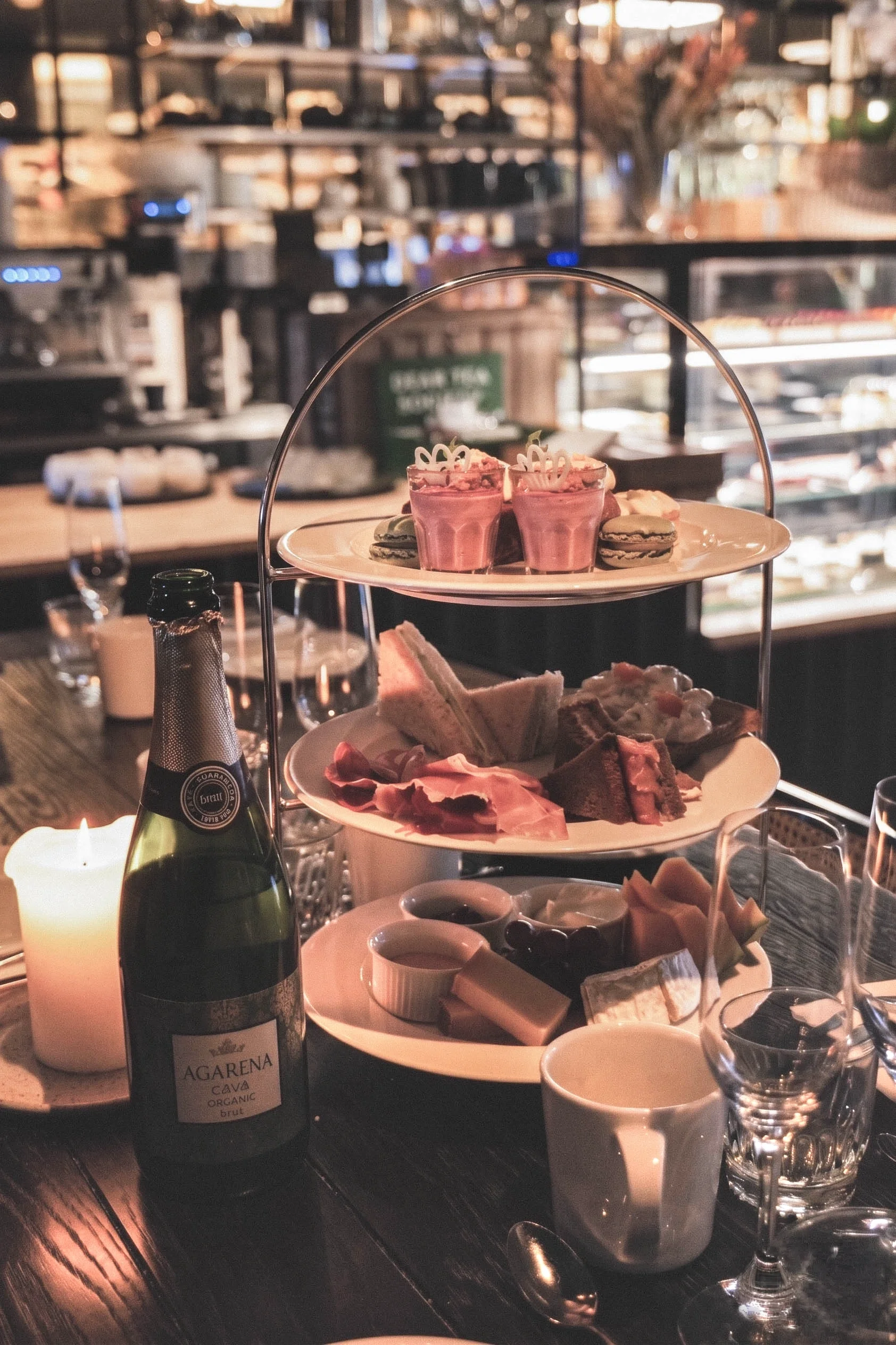 En trevåningsplatå med olika sorters mat, läsk, vin och ljus på ett bord på en restaurang