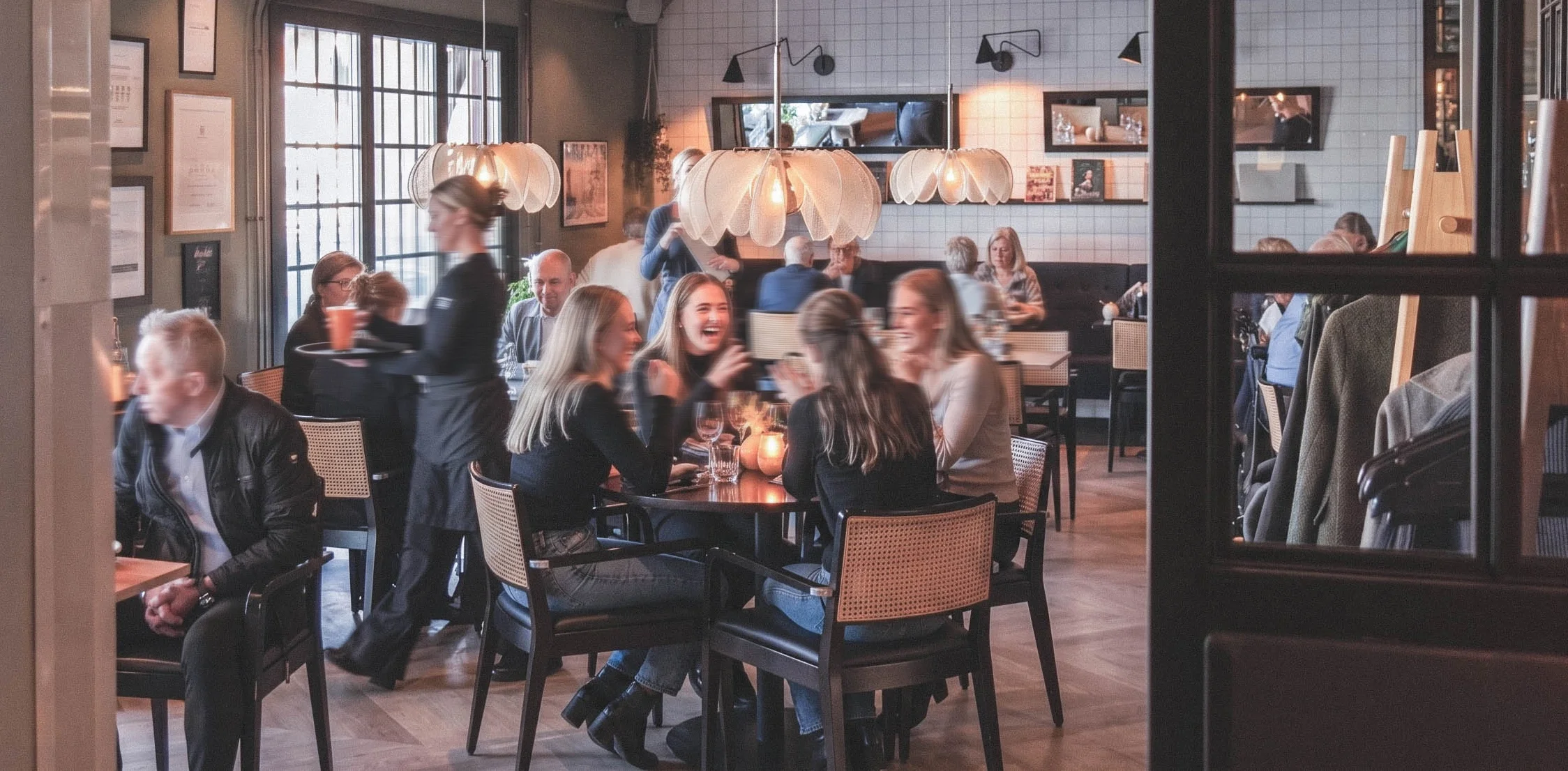Människor som njuter av en middag i en modern restaurang, med ljusa lampor och stora fönster.