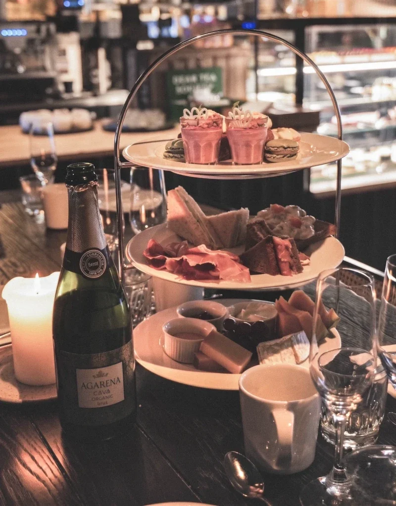 En trevåningsplatå med olika sorters mat, läsk, vin och ljus på ett bord på en restaurang