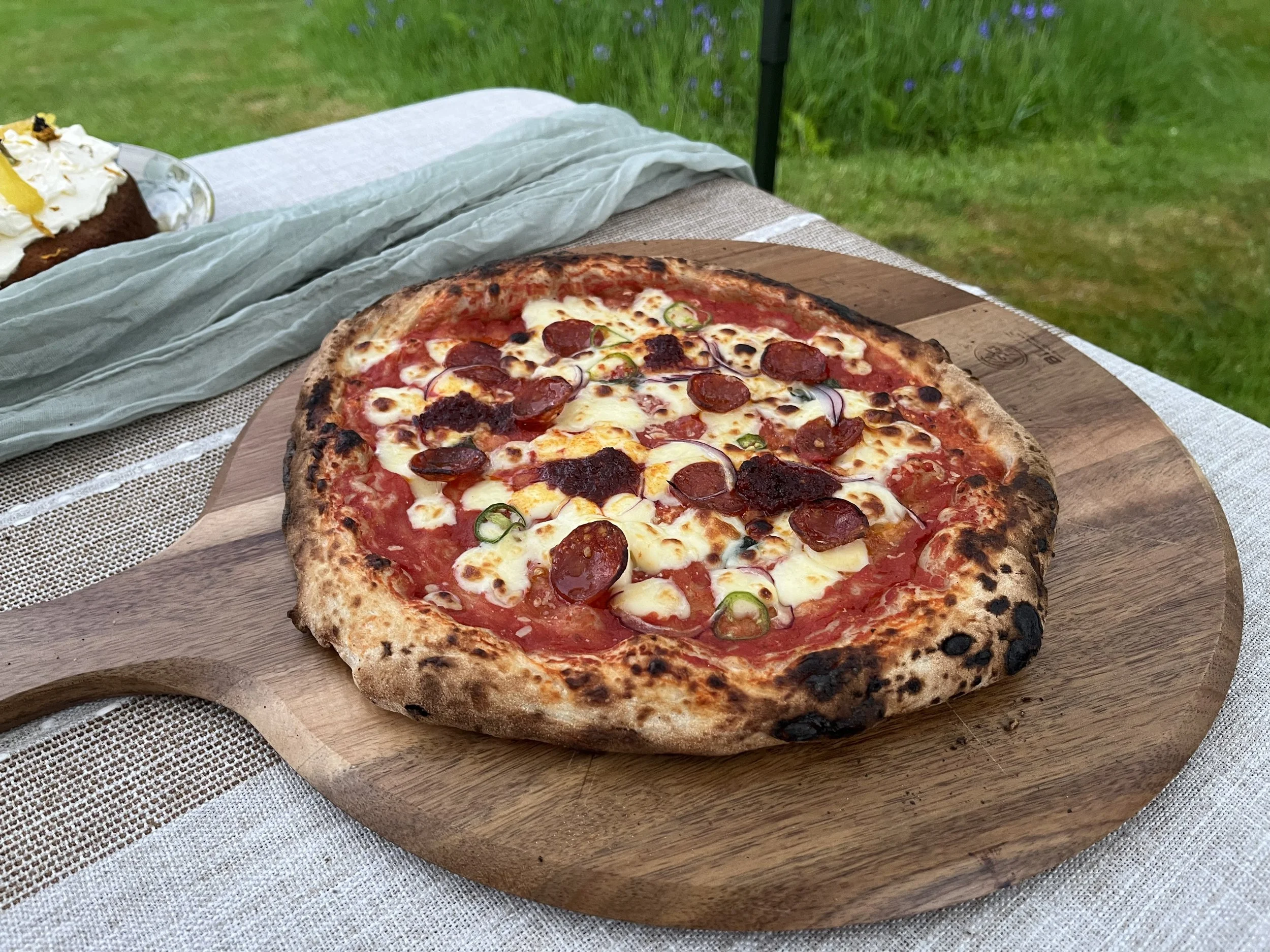 Close-up of a pepperoni pizza with melted cheese on a wooden serving board.