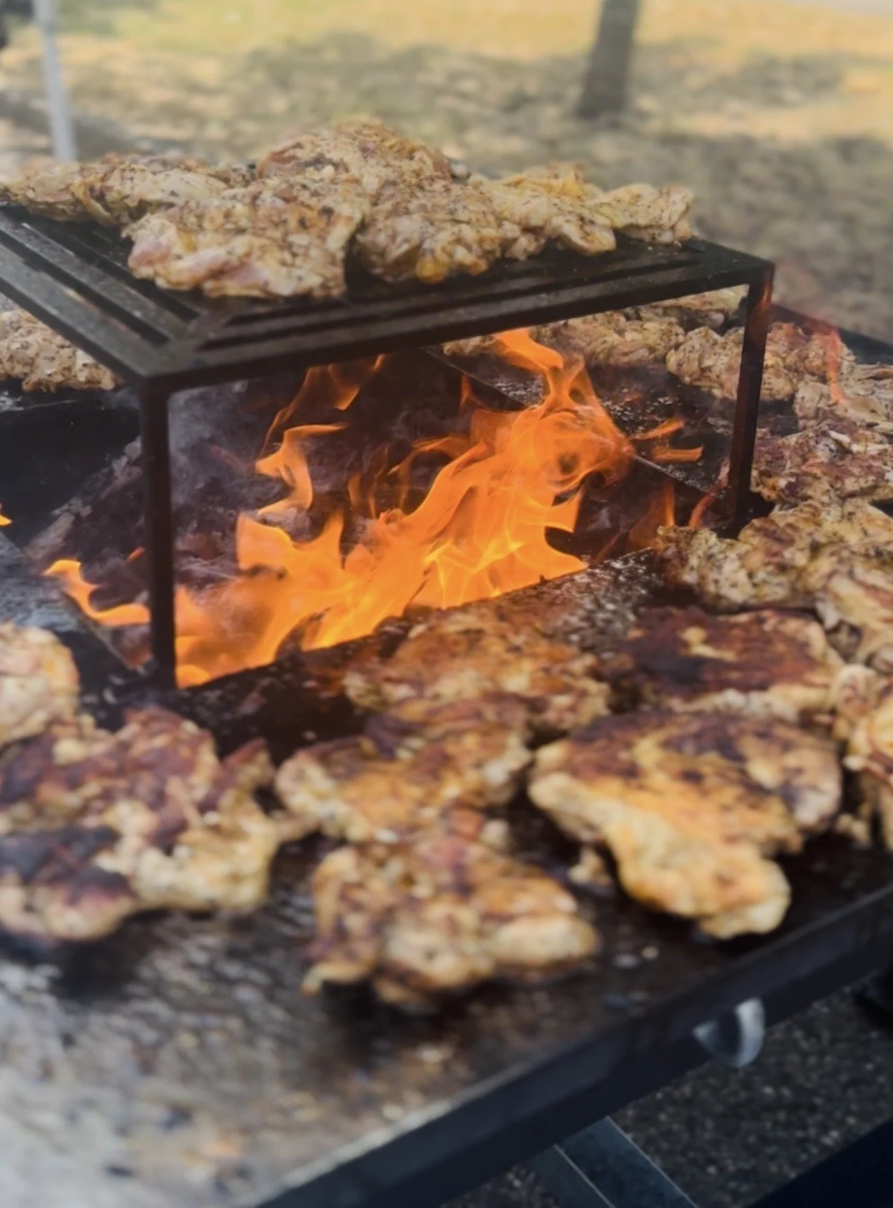 Poulet mariné en train de cuire sur un grill au feu de bois.