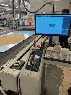 Laboratory setting with computer monitor, testing equipment, and a sheet of material on a workstation