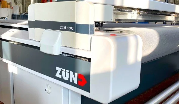 Close-up of a Zünd G3 XL-1600 digital cutting table used in manufacturing or printing industries.