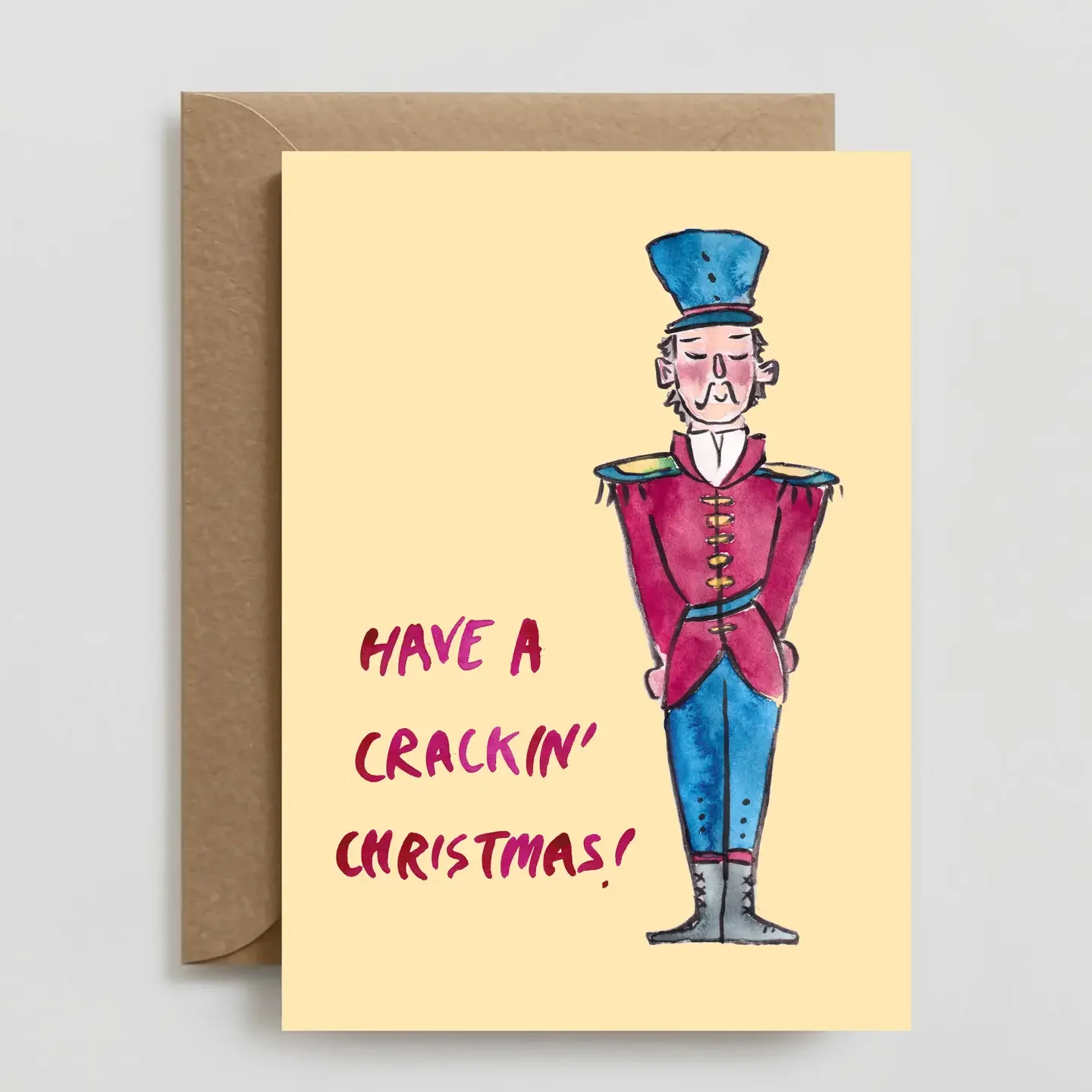 Handmade Christmas card with a cartoon soldier in a red military uniform and tall blue hat, with the text "Have a crackin’ Christmas!" in bold red letters.