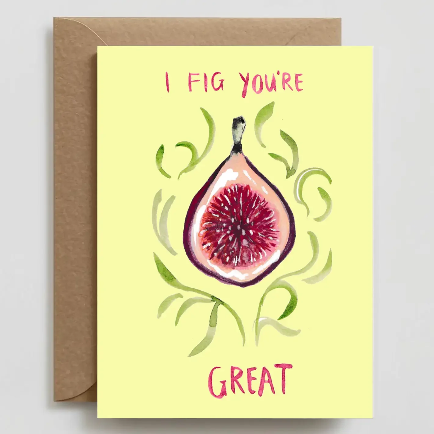 A greeting card with a watercolor illustration of a fig fruit. The fruit is halved, showing its red interior, and green curly lines surround it. The card has the message "I FIG YOU" at the top and "GREAT" at the bottom, written in pink text.