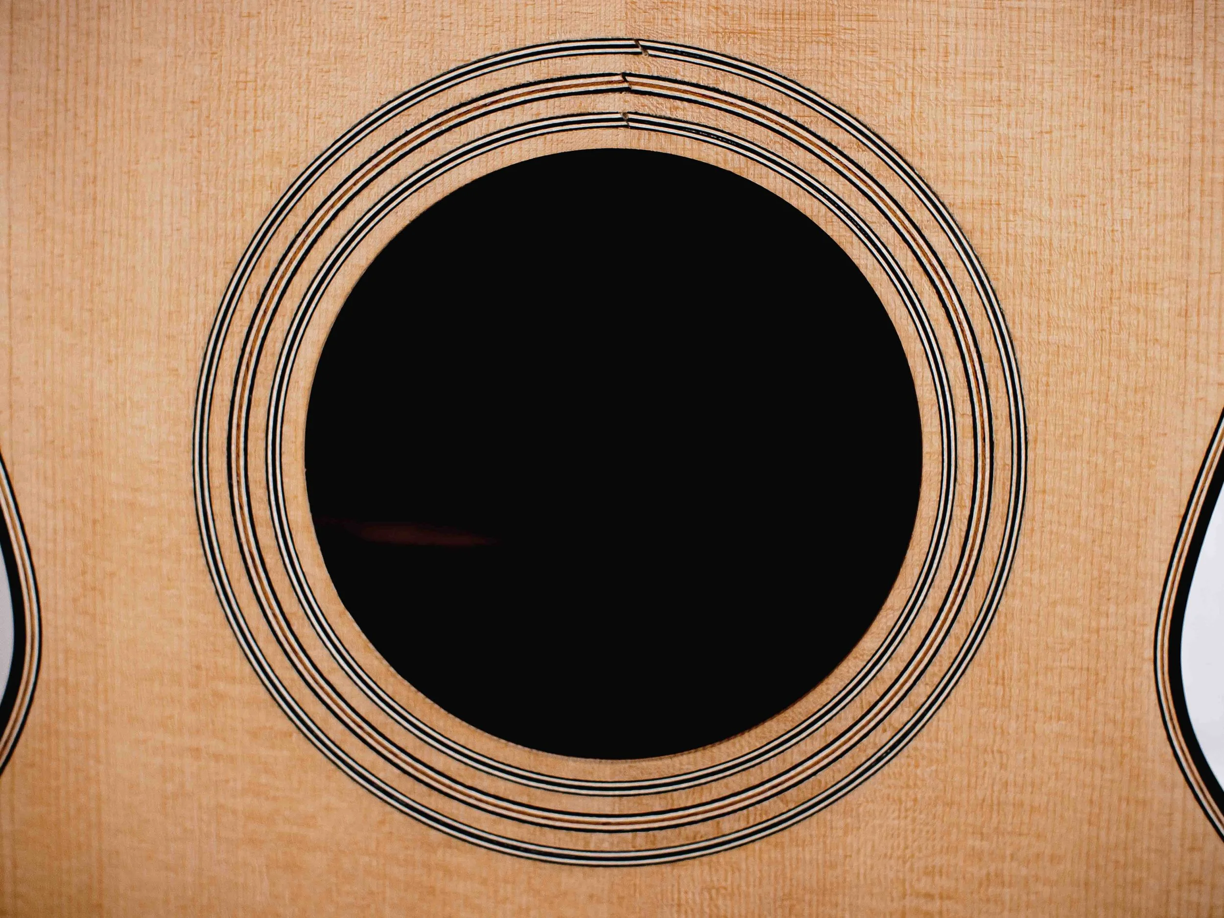 Close-up of a wooden acoustic guitar's sound hole and circular sound hole rosette.