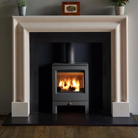 Electric fireplace with a fire burning inside, framed by a white mantel with a picture and potted plants on top.