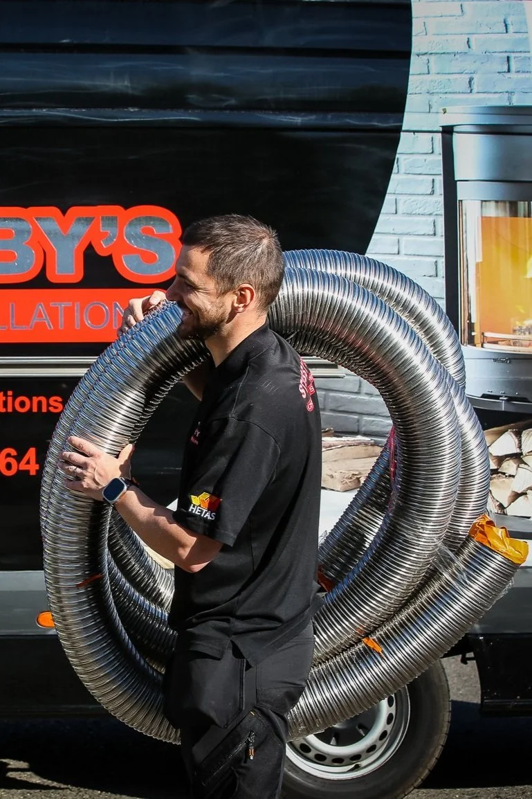 Man carrying large metal ventilation ducts in front of a mobile business sign.