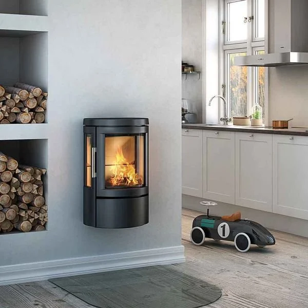 Modern living room with built-in fireplace on the wall, stacked firewood, and a toy race car on the floor near the kitchen.