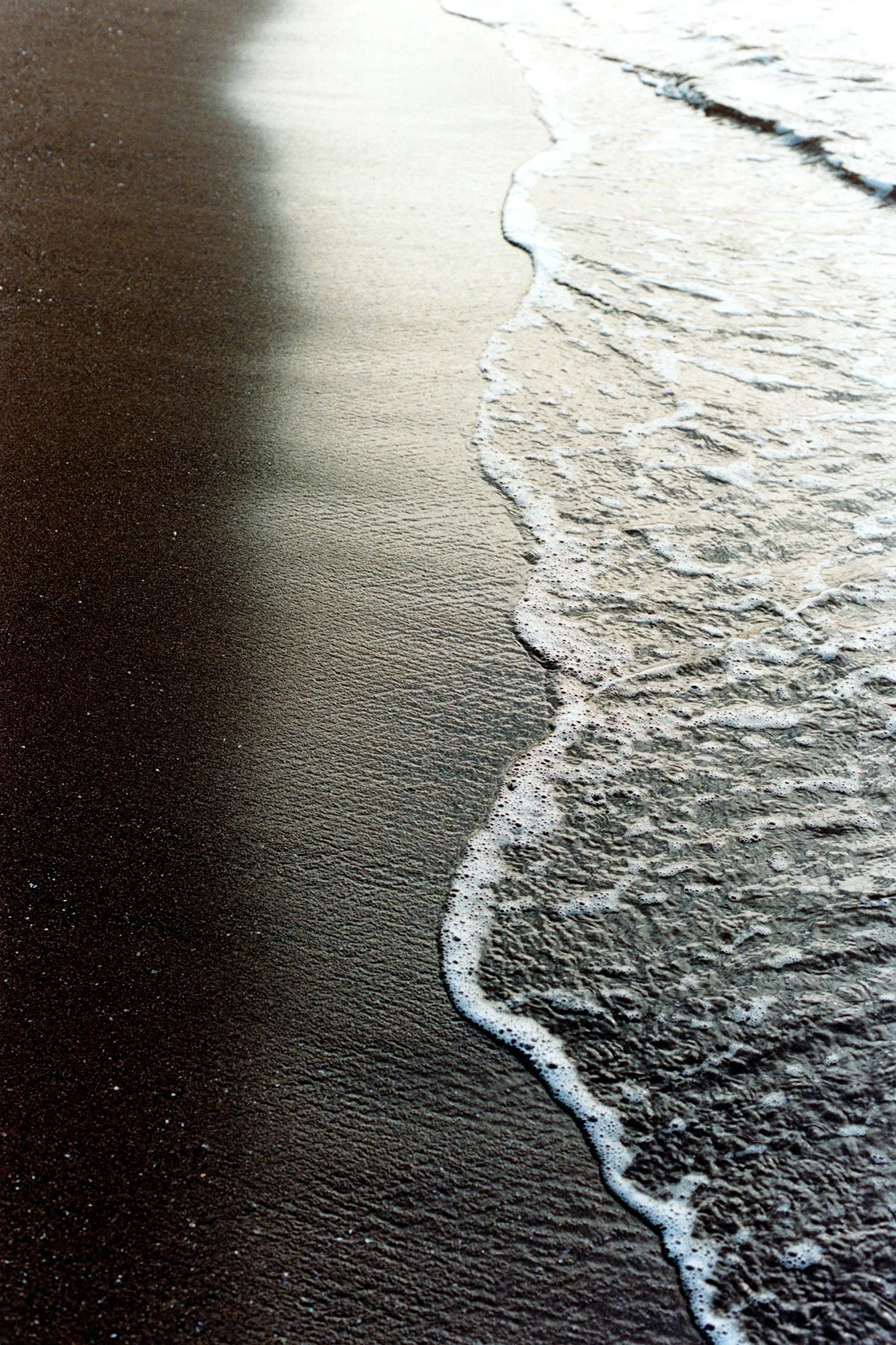 Vague image d'une plage avec sable noir et des vagues d'eau qui déferlent.