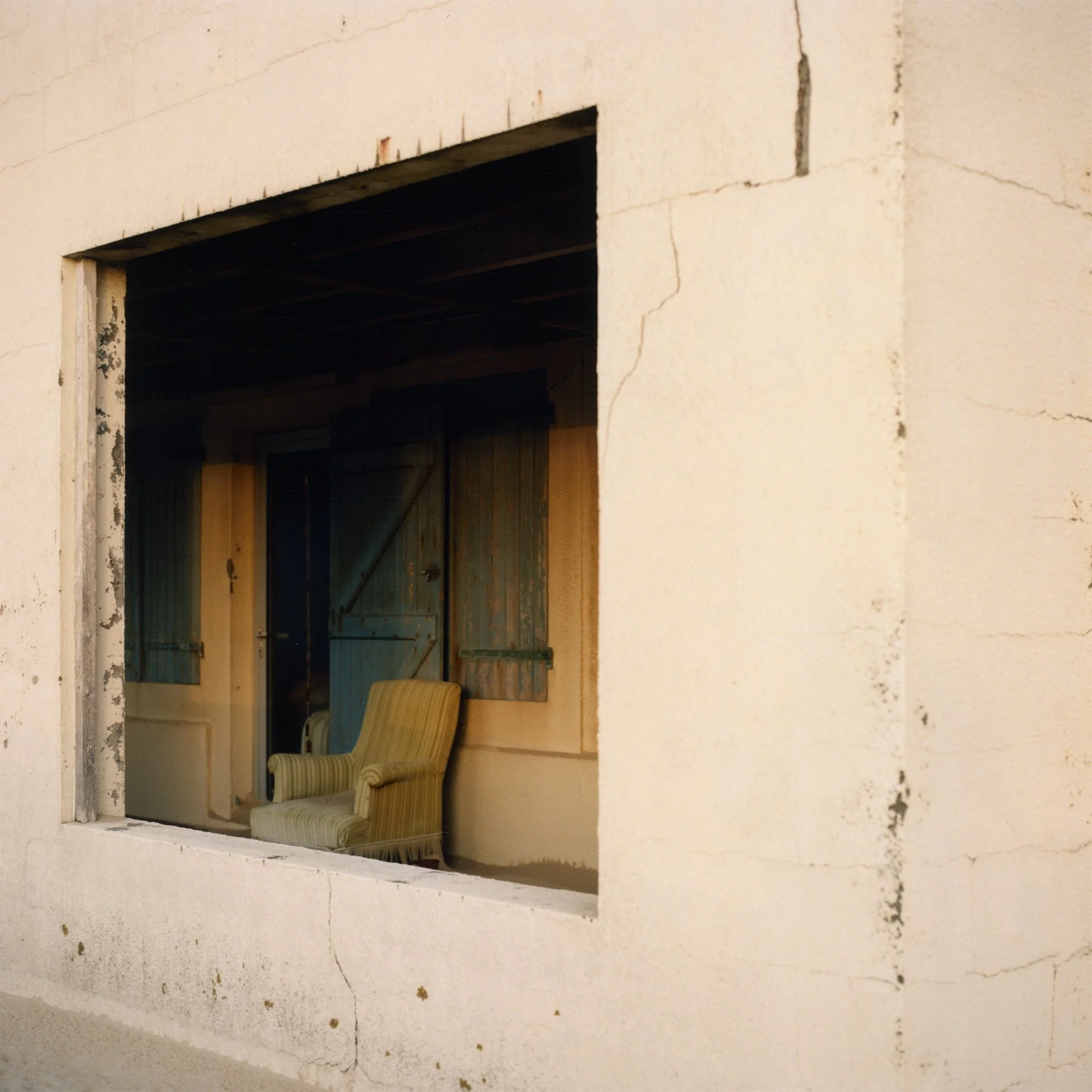 Vue d'une ouverture dans un mur en béton non fini, montrant l'intérieur d'une pièce sous construction avec des poutres en bois.