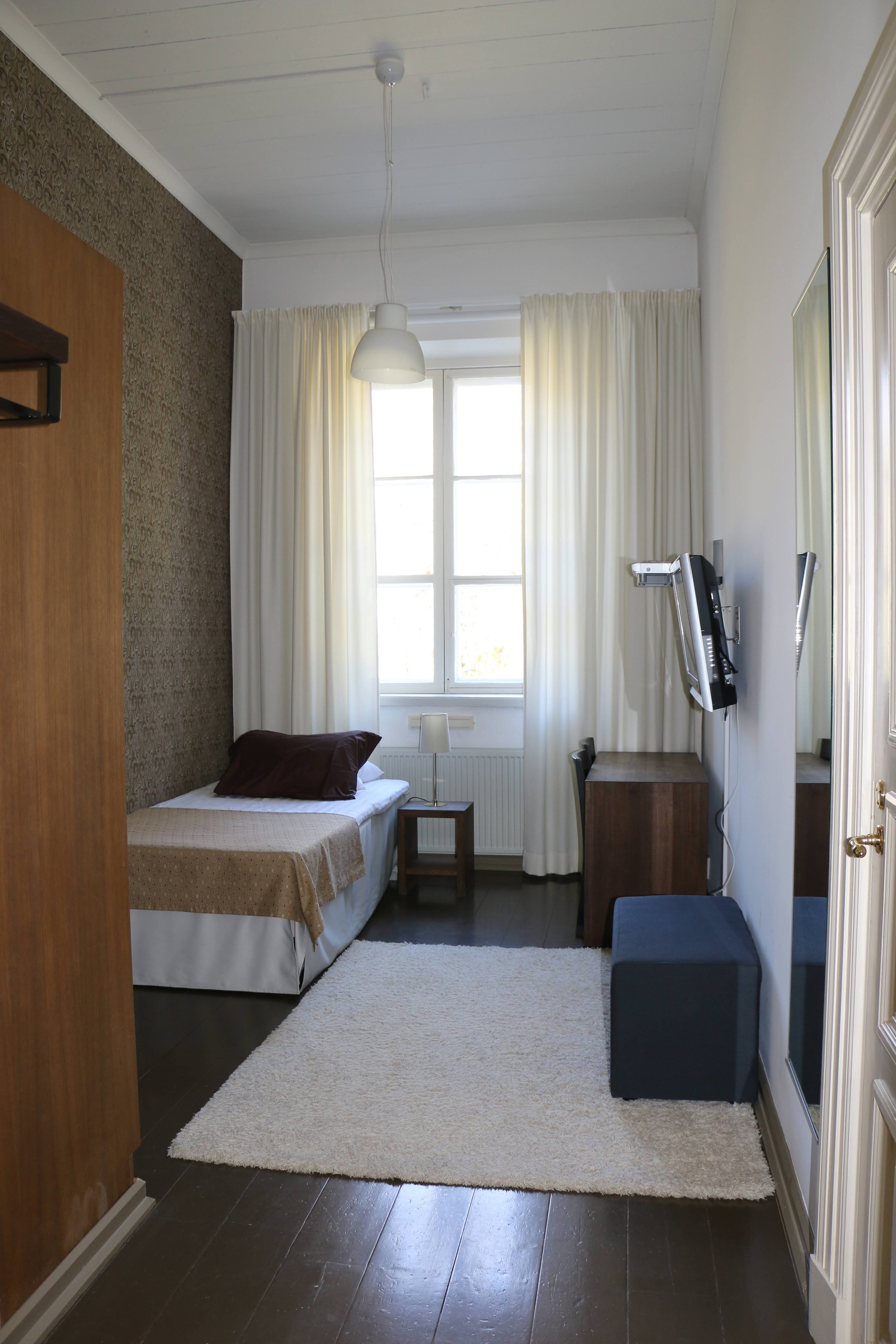 kuva yhden hengen huoneesta missä yksi sänky