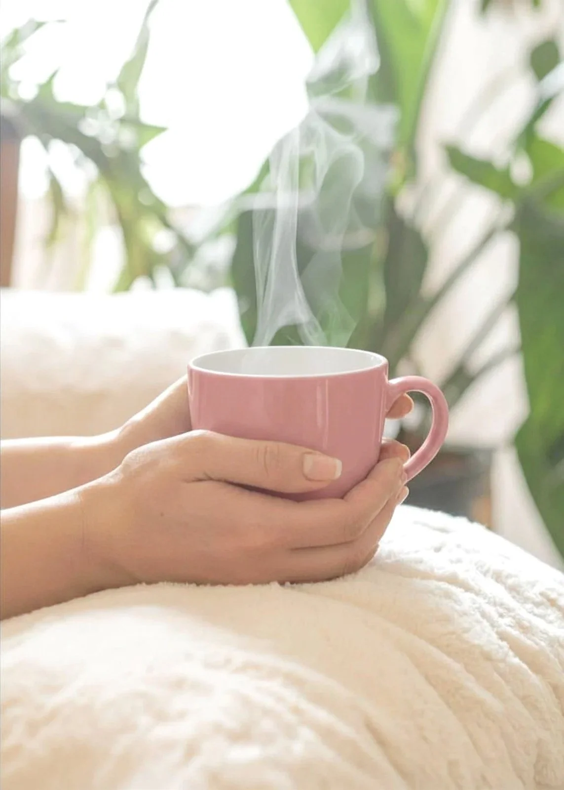 Woman holding a warm drink during an online therapy session.