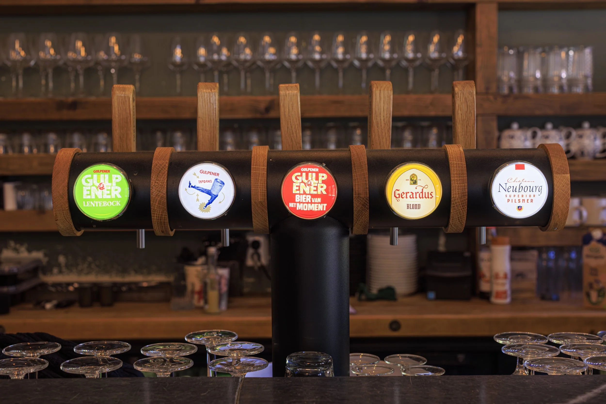 Een bar met een tapinstallatie voor bier, met verschillende taps en glazen eronder.