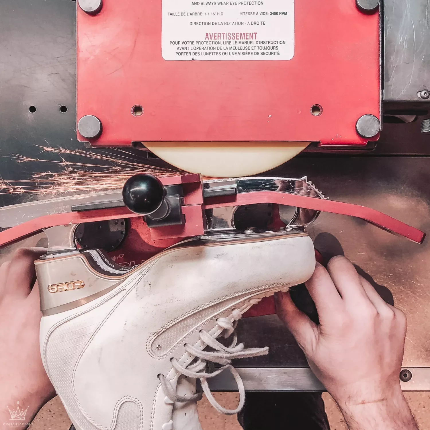 A person sharpening a figure skate on a sharpening machine that is sparking.