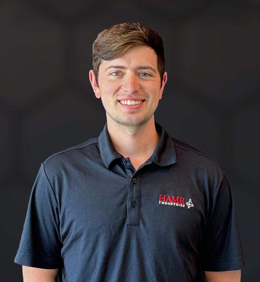 Portrait of a young man with brown hair, wearing a dark gray polo shirt with a logo that says HAMR on the left chest.