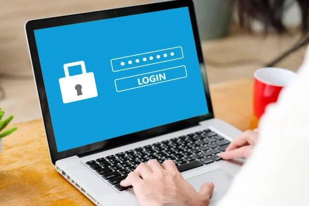 Laptop screen displaying a login page with a padlock icon and password input, person typing on keyboard.