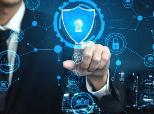 Businessman in a suit touching a digital shield icon representing cybersecurity and data protection on a virtual interface over a city background.