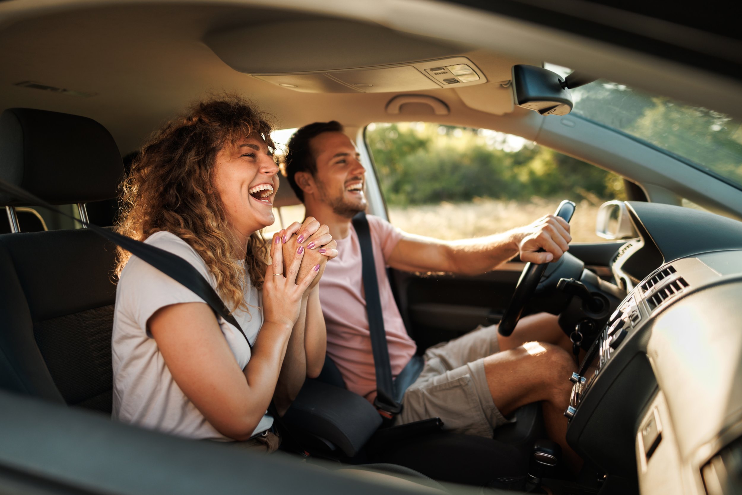 A smiling woman and man in the car, with the woman excited and the man driving.