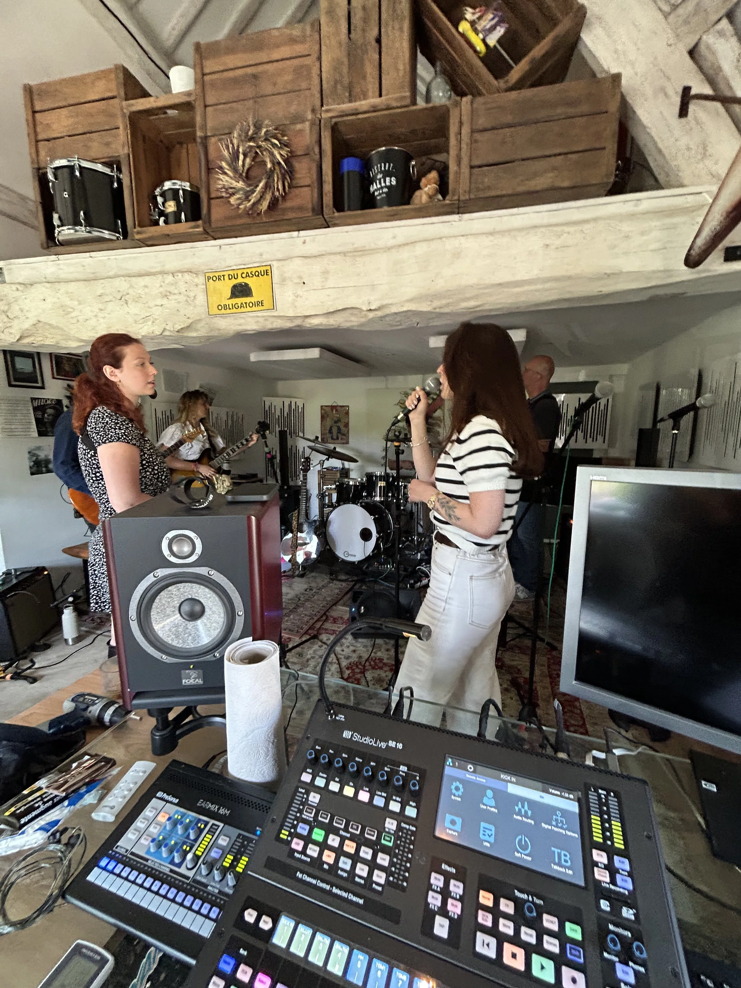 Une répétition de groupe de musiciens dans une pièce intérieure avec un équipement audio et un décor vintage.