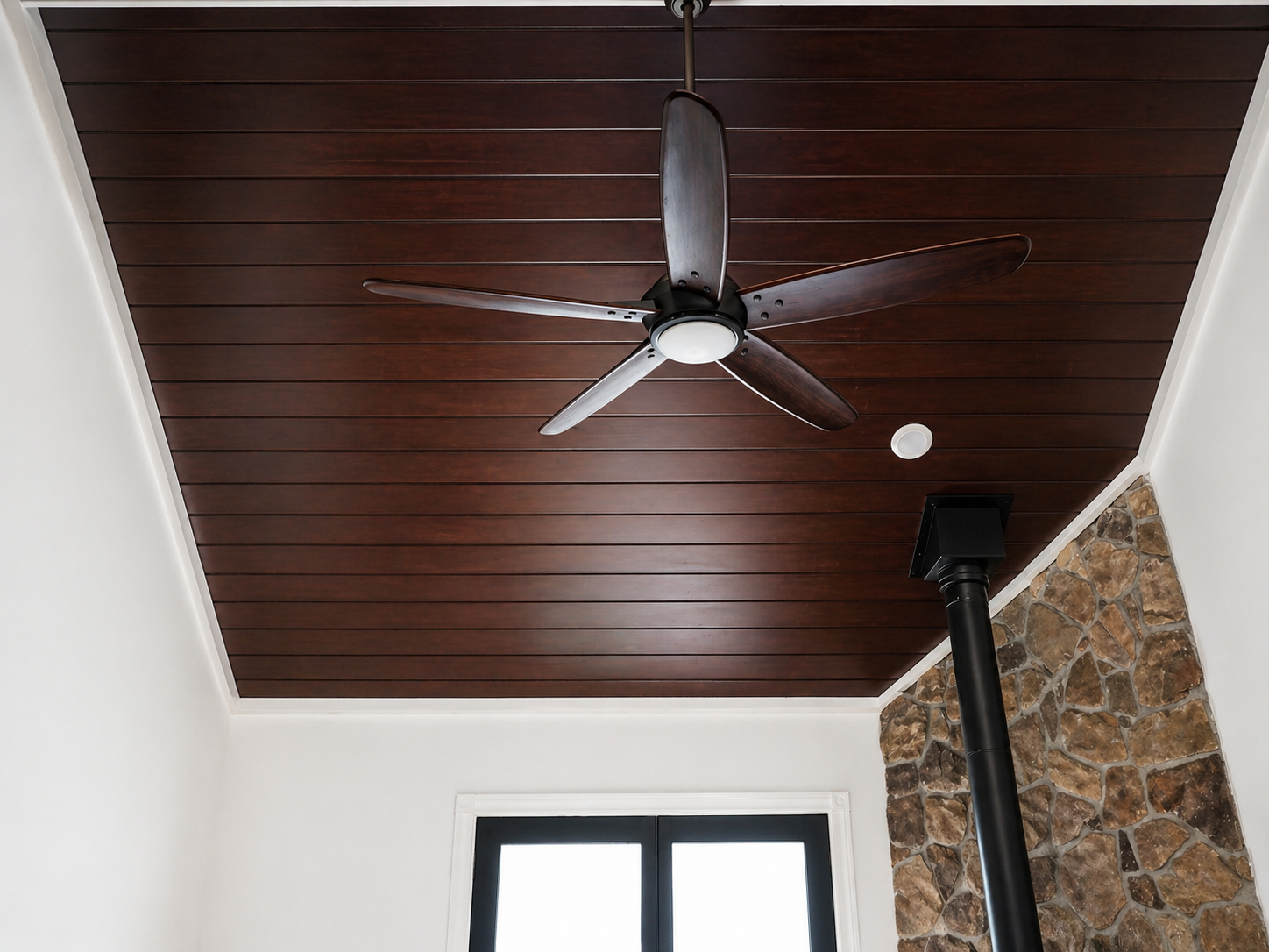 This project highlights a beautifully finished ceiling feature that adds warmth, character, and architectural interest to the space. Rich wood planks create a custom upscale look, while the modern ceiling fan adds both function and style. The contras
