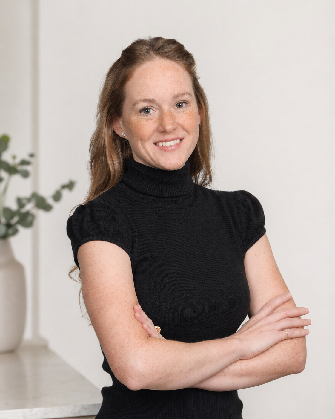 Woman with a warm, bright smile, arms folded, in a professional headshot picture