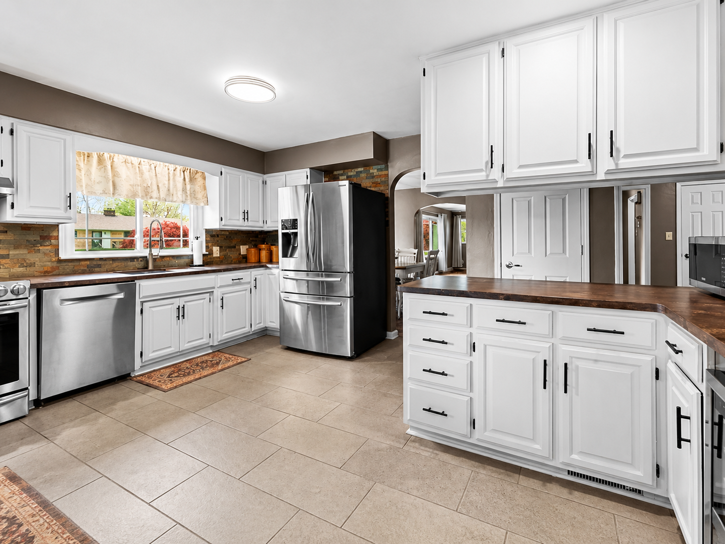 bright white kitchen cabinets, butcher block countertop, tile flooring, custom backsplash, recessed lighting, kitchen remodel, prelisting kitchen update