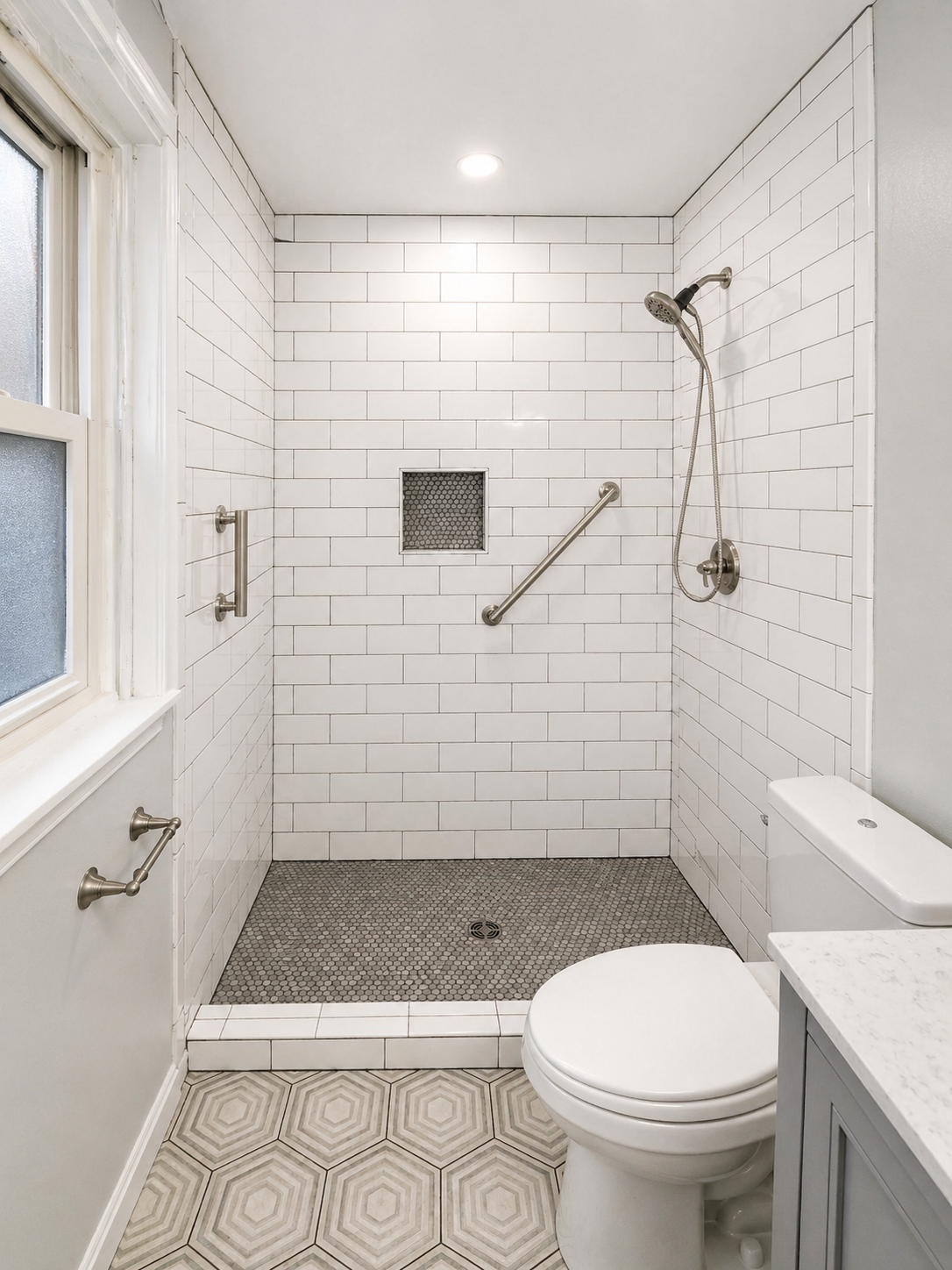 Bathroom remodel with walk-in shower, white subway tile, recessed shower niche, grab bars, penny tile shower floor, and patterned floor tile.