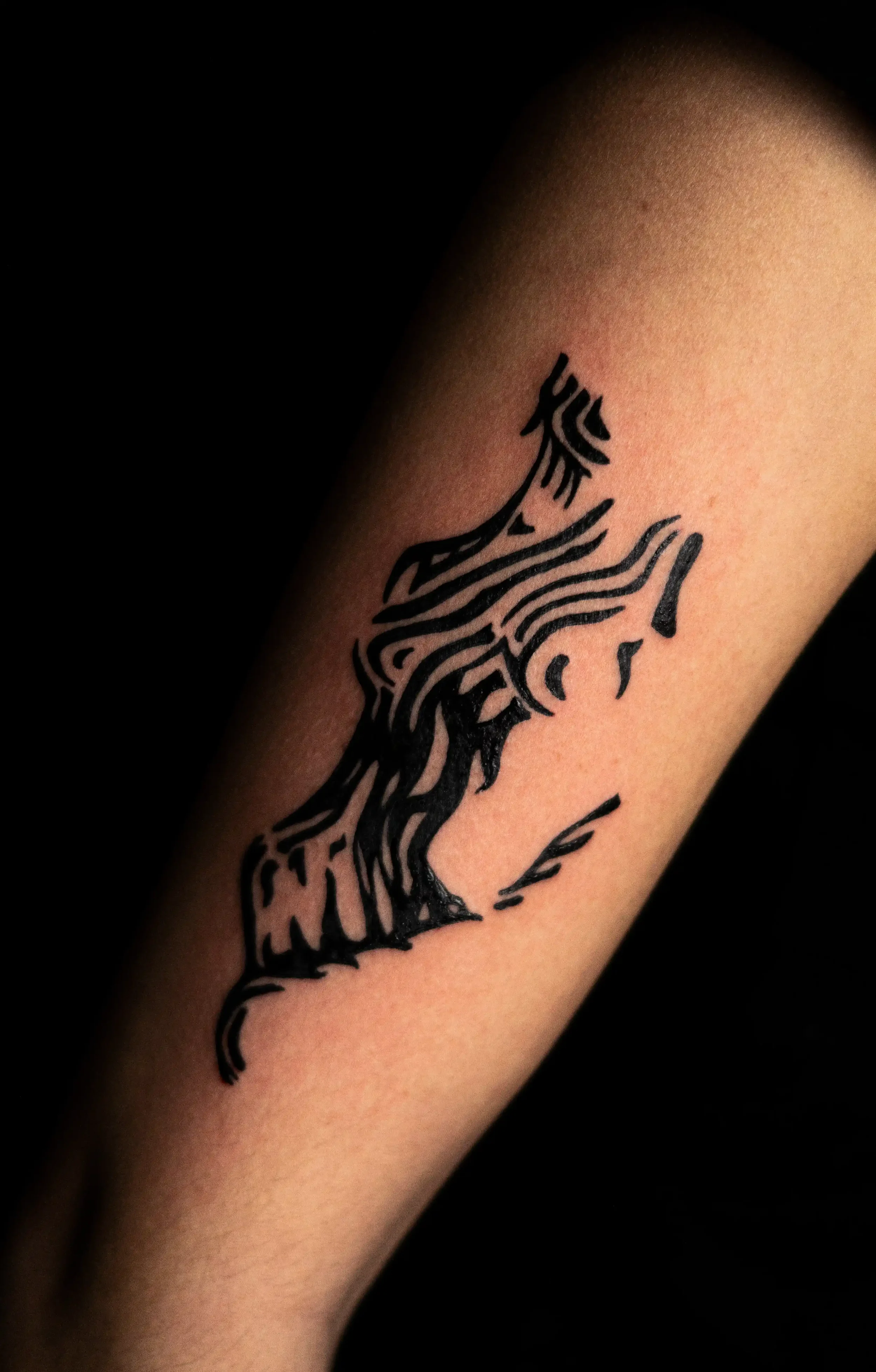 Tattoo in schwarzer Tinte auf dem Oberarm, abstraktes Design, Linienmuster, südseeartige Elemente.