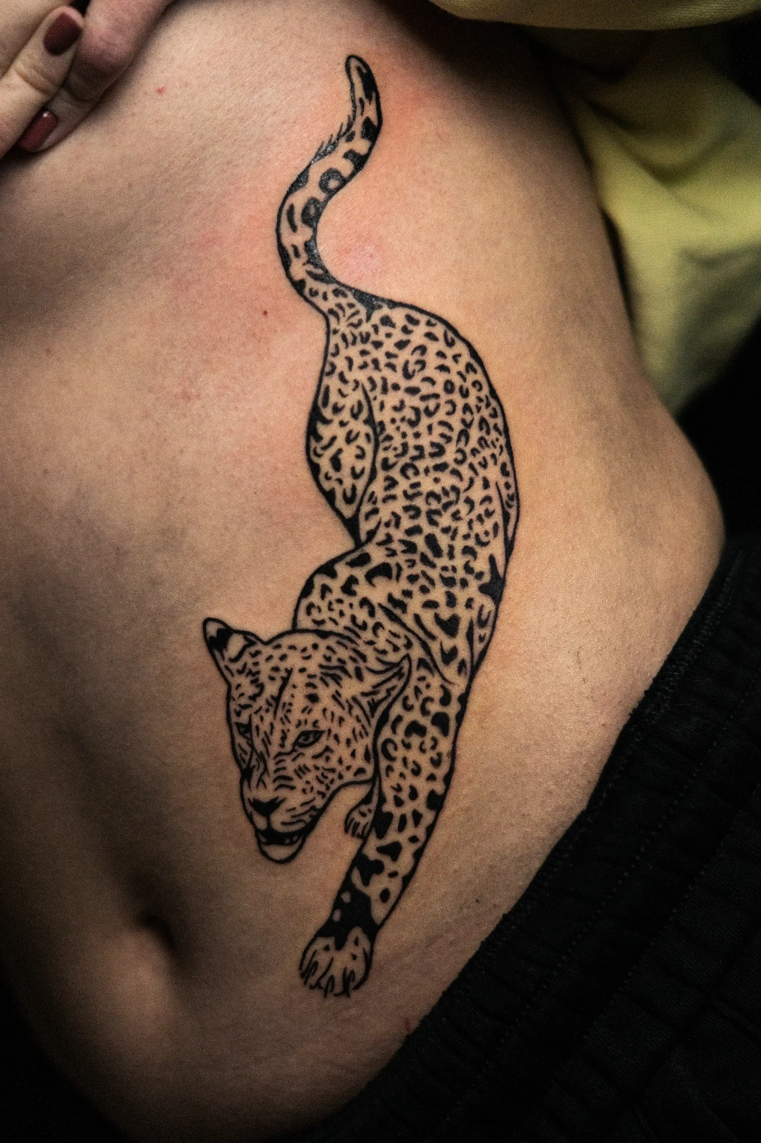 Tattoo eines Leoparden, das die Seite eines Körpers entlang läuft.