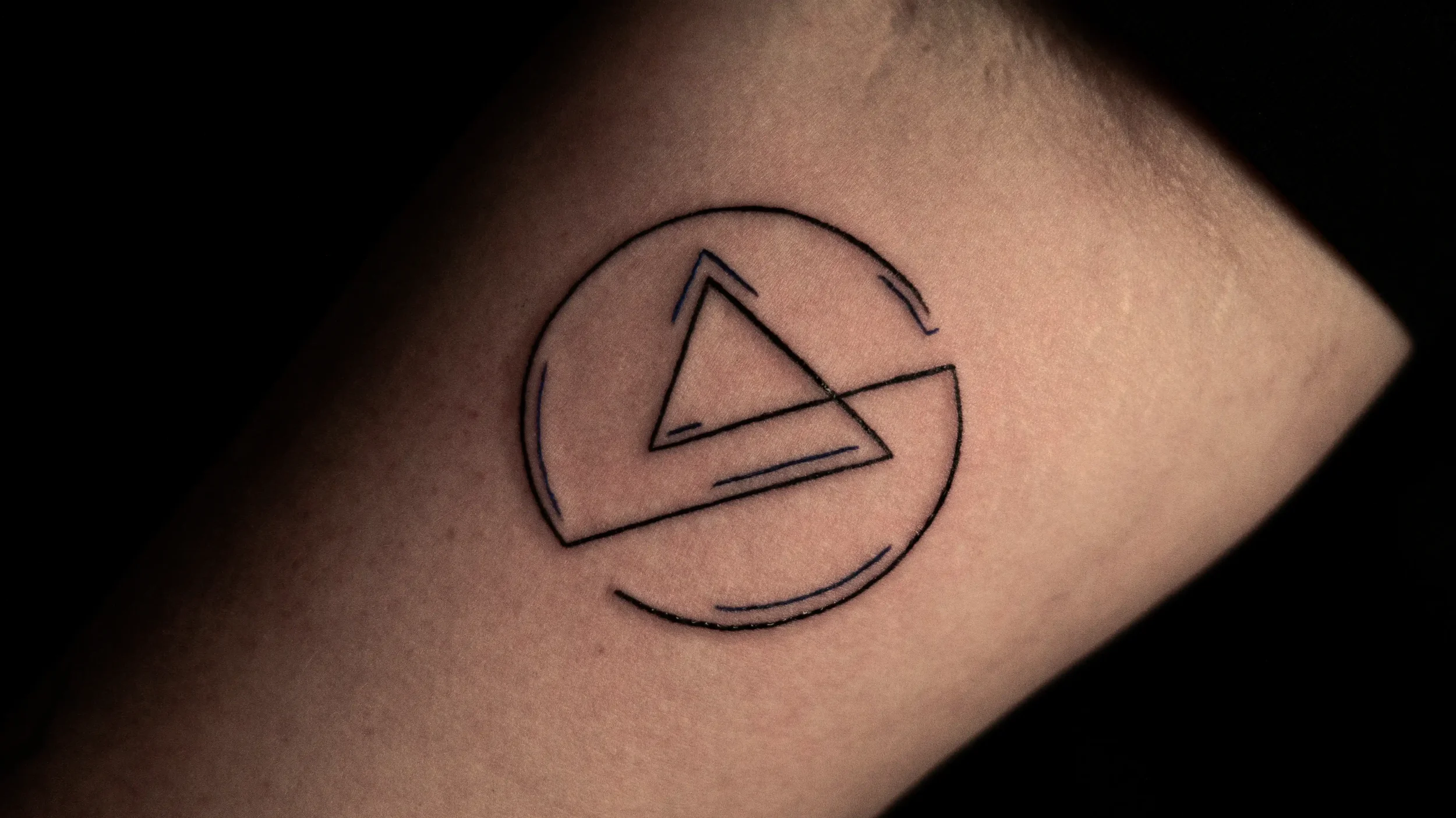 Tattoo eines geometrischen Symbols auf Haut, bestehend aus Linien innerhalb eines Kreises