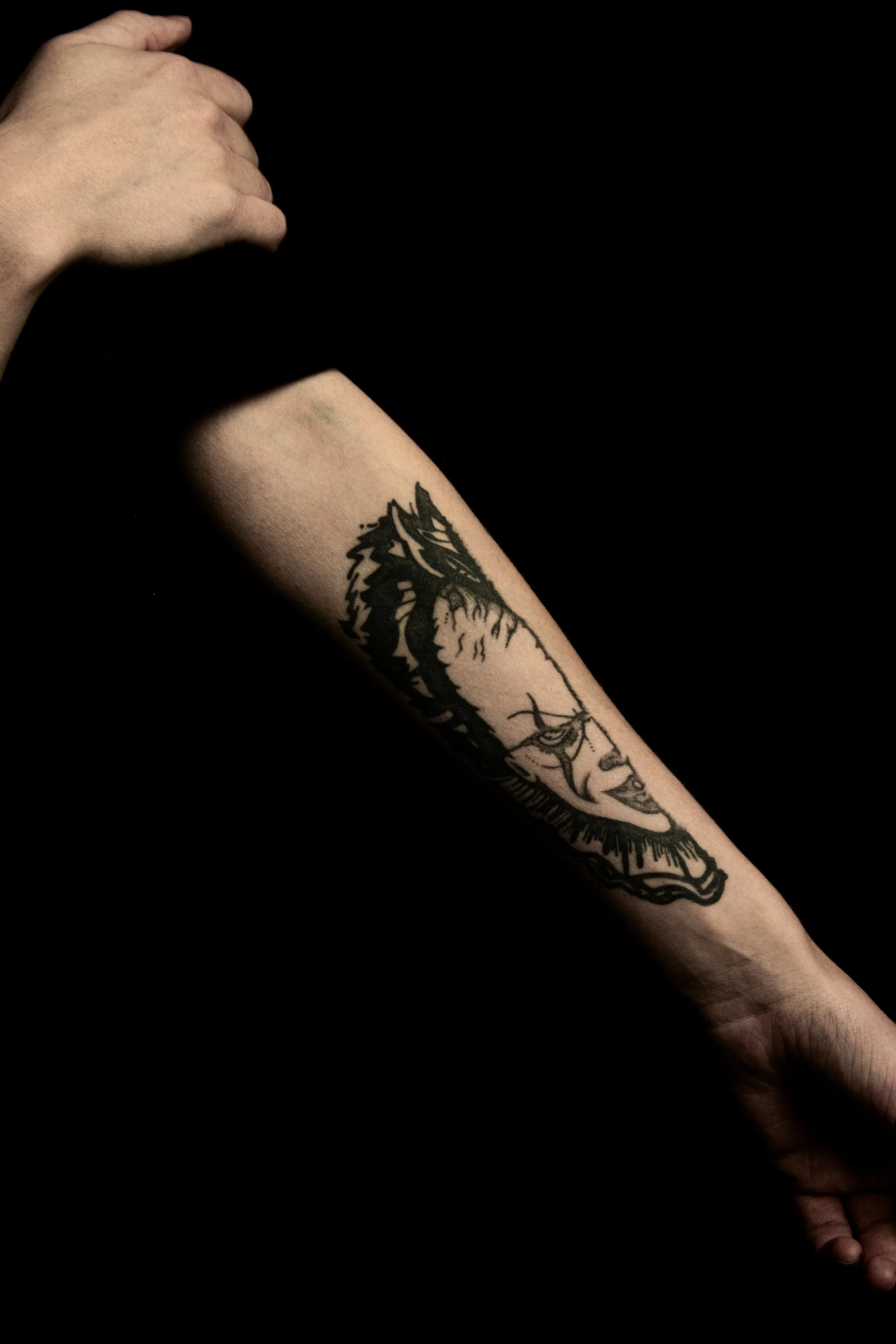 Nahaufnahme eines menschlichen Arms mit Tattoo vor einem schwarzen Hintergrund.