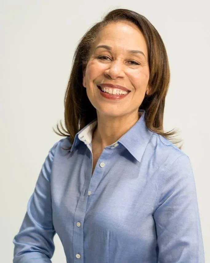 Kelley Powell on camera look with shoulder-length brown hair wearing a light blue button-up shirt against a plain light background.