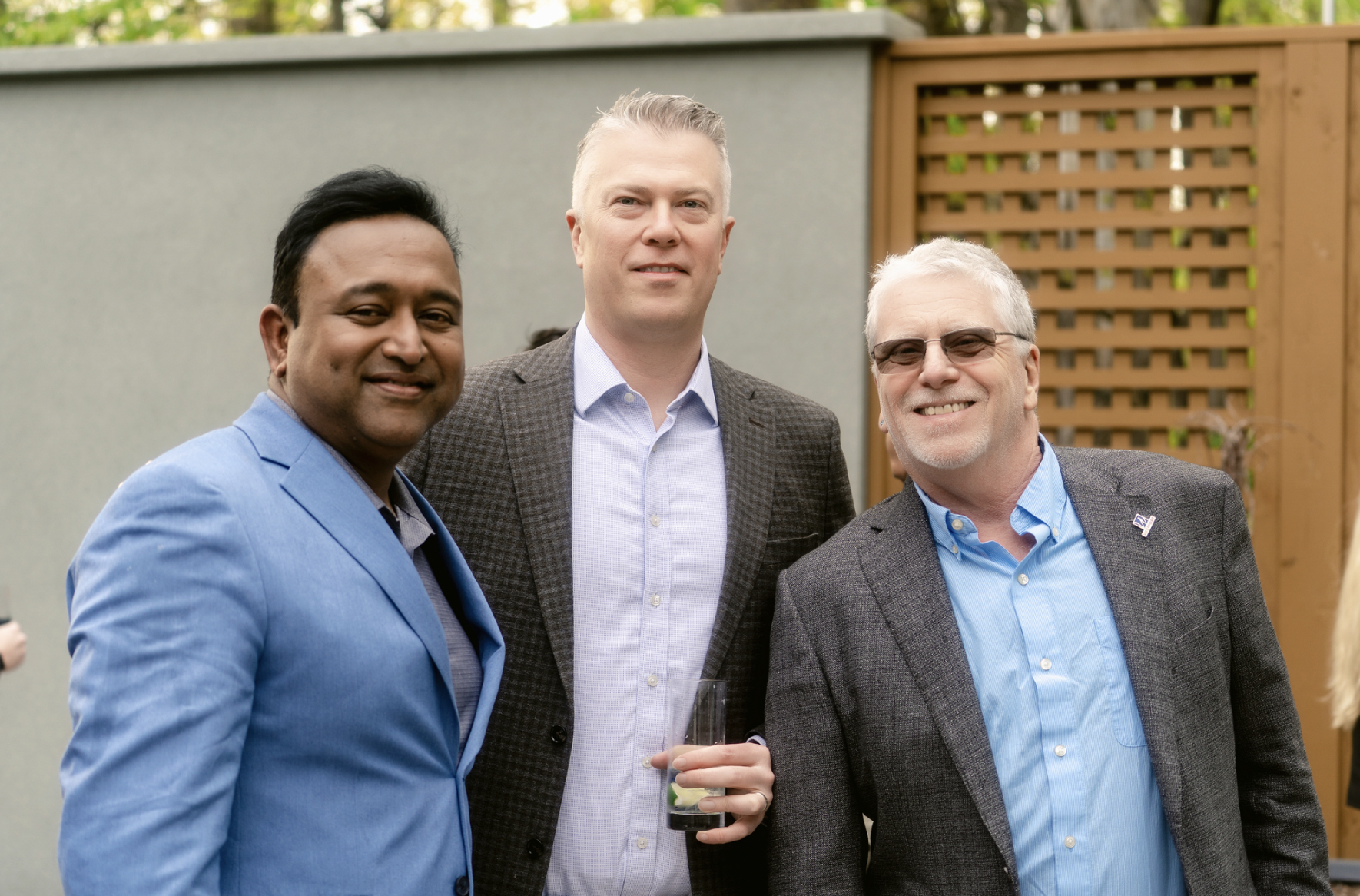 Matt Mandell and others standing outside, smiling at the camera, with one holding a drink in his hand, during a social event or gathering.