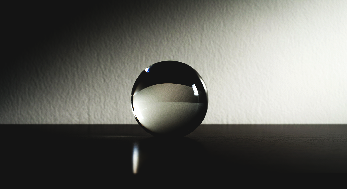 A glass sphere placed on a dark surface, reflecting a room with a light-colored wall and a window.