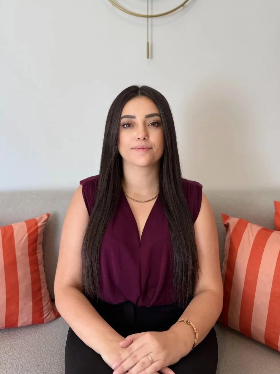 Kadın oturma odasında otururken görüldüğü, arka planda duvarda saat olduğu bir fotoğraf.