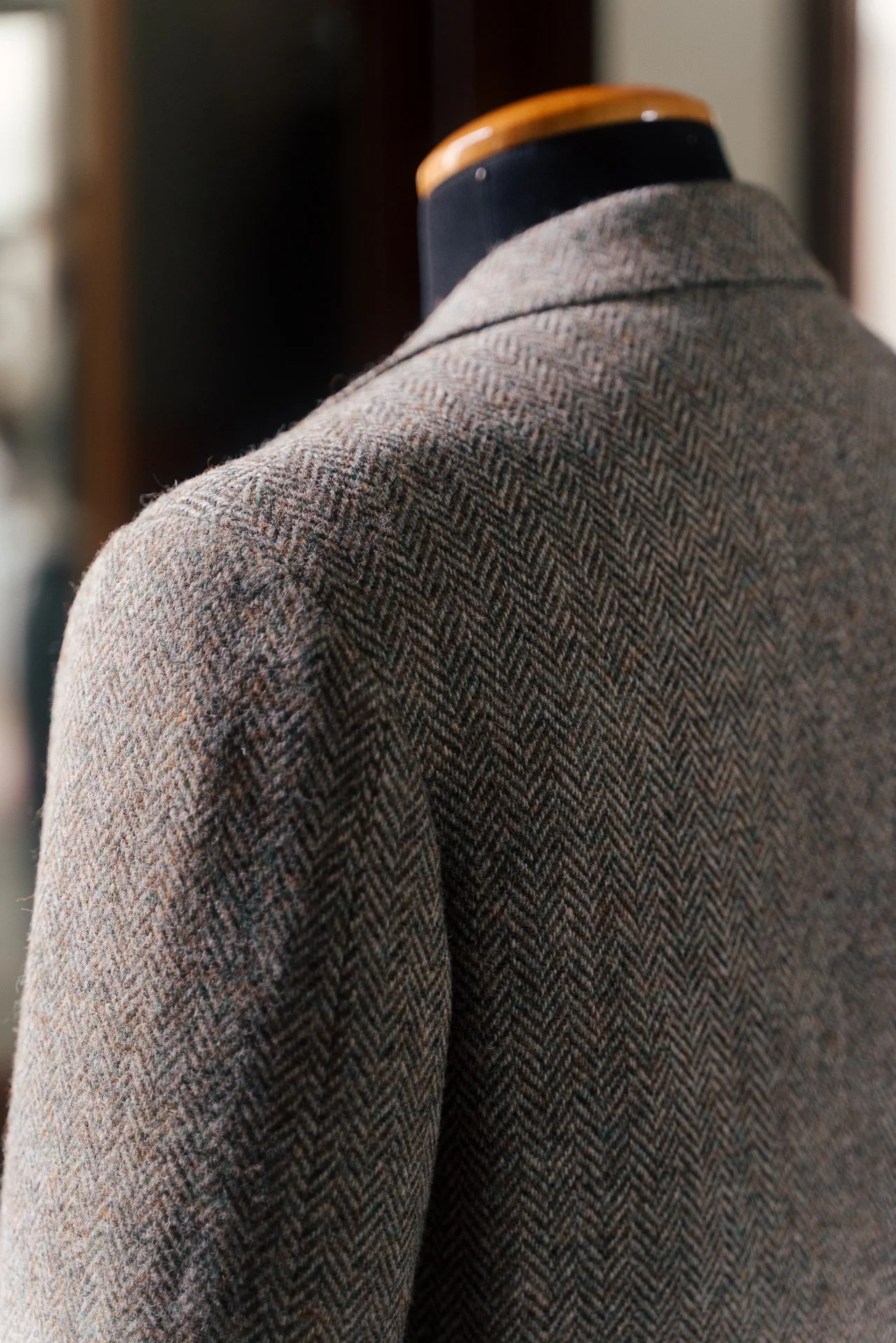 Close-up of a mannequin wearing a brown tweed blazer with a herringbone pattern.