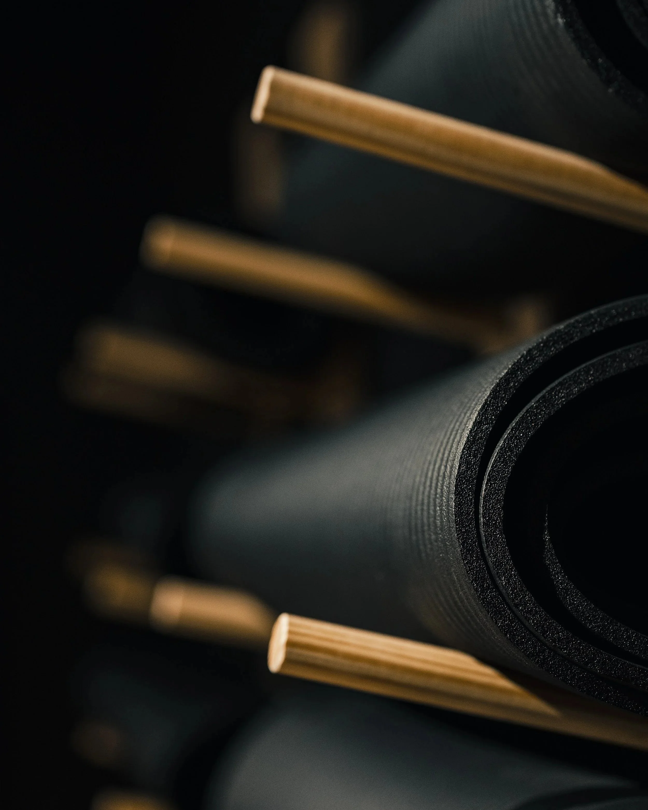 Close-up of a rolled-up black telescope or mechanical tube with gold-colored ends, set against a dark background.