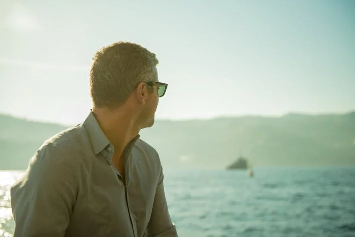 Paulino Duran wearing sunglasses looking out at the water during sunset