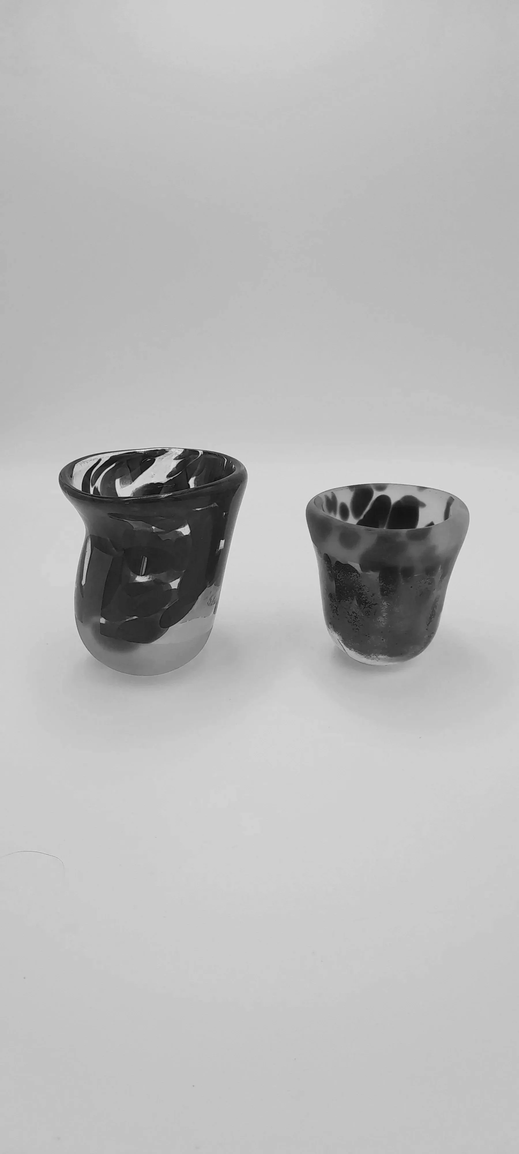 Two black and white marbled ceramic cups, one larger and one smaller, on a white surface.