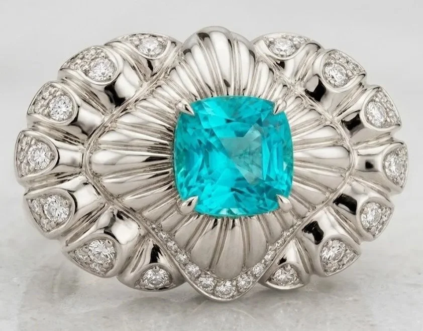 Une bague en or blanc ornée d'une Tourmaline Paraiba au centre, entourée de petits diamants.