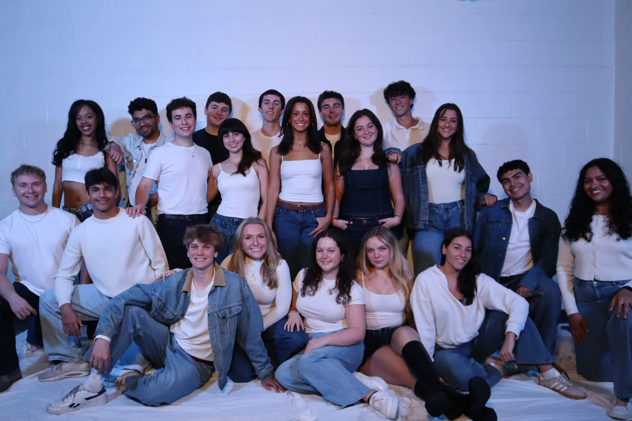 Group of young adults posing together in a brightly lit room, smiling for the camera.