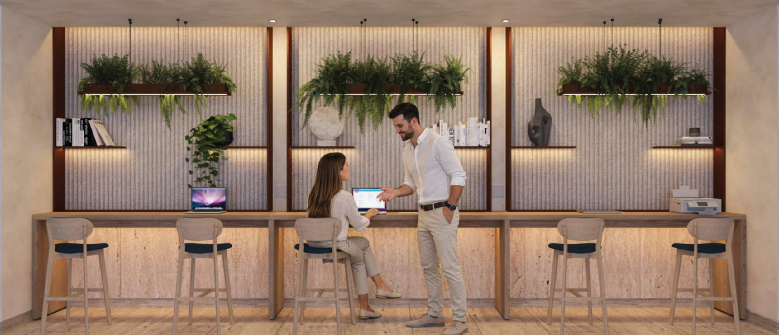Dos personas conversando en una oficina moderna con paredes decoradas con plantas y libros. Una mujer sentada en una silla frente a un escritorio con una computadora portátil y un hombre de pie frente a ella, hablando.