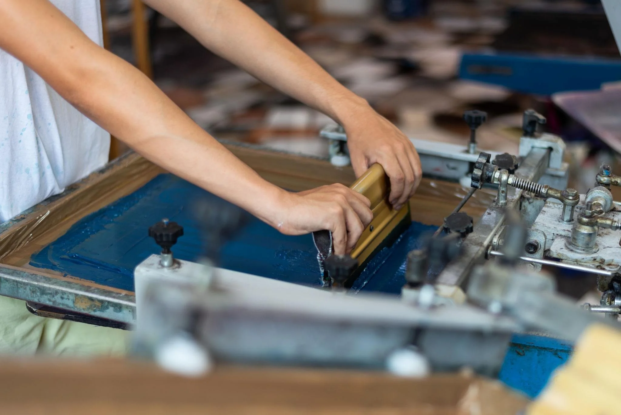 Printer pulling ink across a screen during the custom screen printing process.