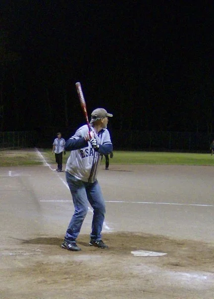 Person preparing to bat at a baseball field during nighttime.