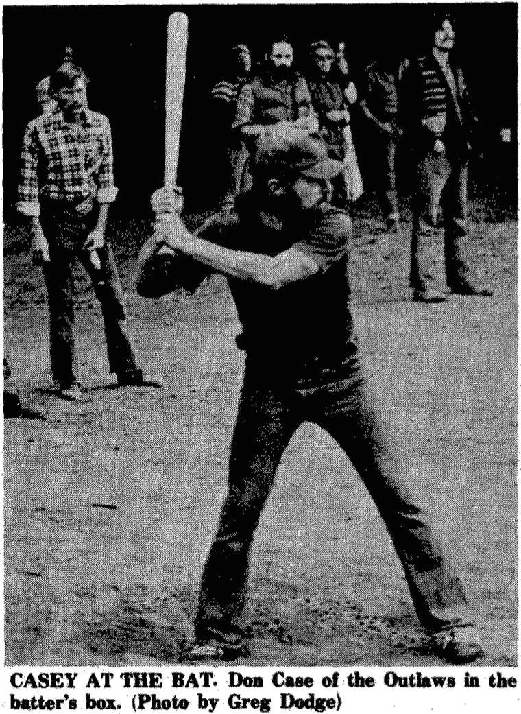 Black and white photo of a boy named Don Casey in a baseball batting stance with a bat, standing in front of a group of people. The caption reads, "CASEY AT THE BAT. Don Case of the Outlaws in the batter's box. (Photo by Greg Dodge)."